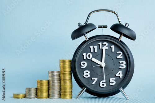 Alarm clock and step of coins stacks, time for savings money concept. shallow focus.