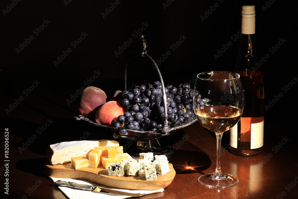 Cheese, wine and fruit on a dark background