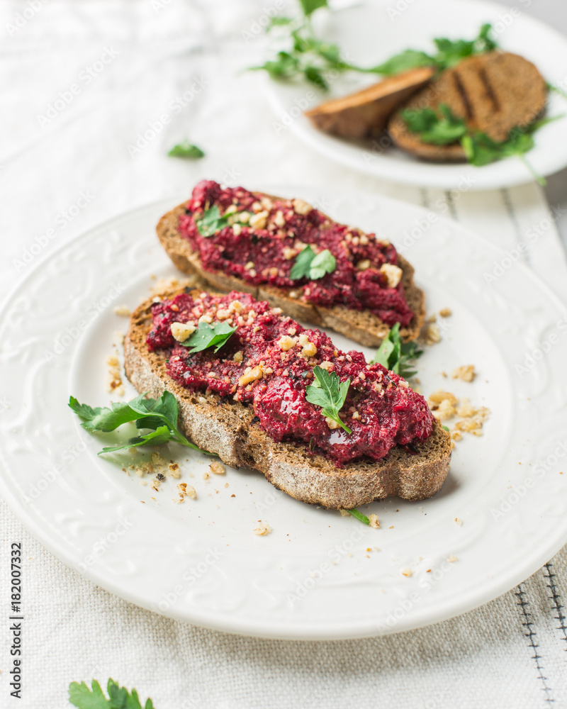 Homemade toast from whole grain bread with beet paste, greens and nuts. Light concrete background, white soft. Place for text. Food photo with hands. Useful dietary baking. Flat lay, top view Homemade toast from whole grain bread with beet paste, greens and nuts. Light concrete background, white soft. Place for text. Food photo with hands. Useful dietary baking. Flat lay, top view