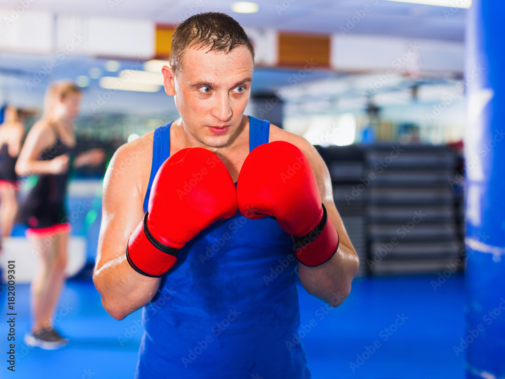 Man boxer is training in gloves in gym.