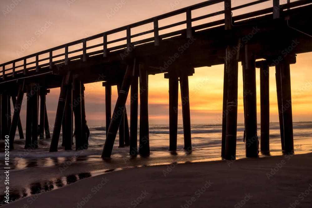 Sunset beach view through pier silhouette