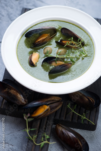 Spinach cream-soup with mussels and olives, selective focus, vertical shot