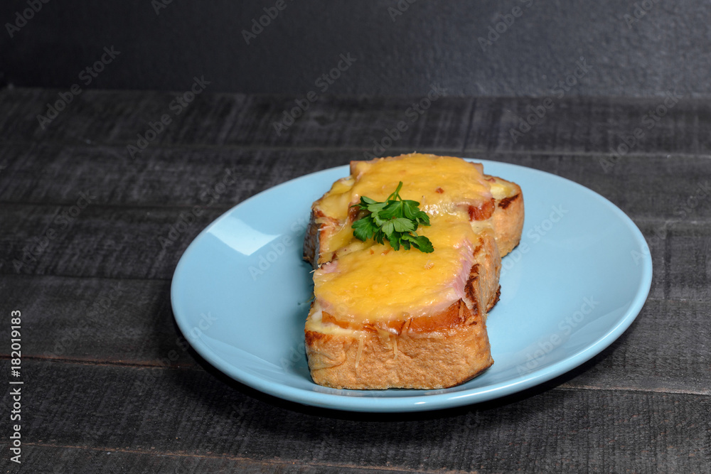 Sandwich with meat, cheese and greens on a blue plate Sandwich with meat, cheese and greens on a blue plate