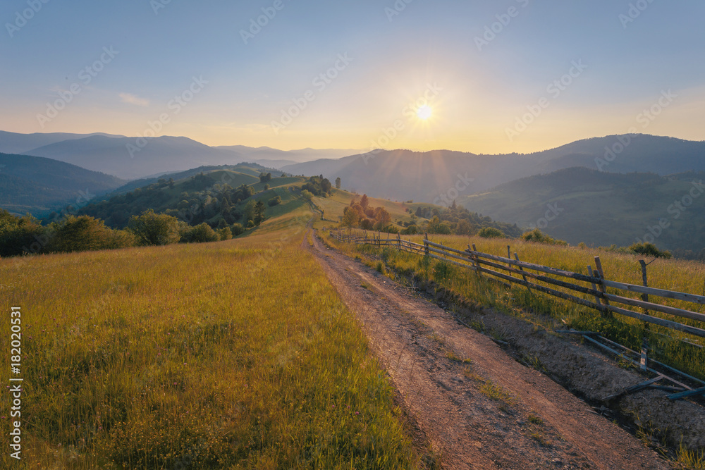 Rural mountain landscape hills with road in scenic sunset light.