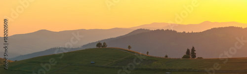 Wide panorama. Rural mountain landscape hills in scenic sunset light.