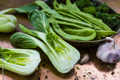 Fresh and raw Chinese cabbage pak choi and green peas on vintage background.