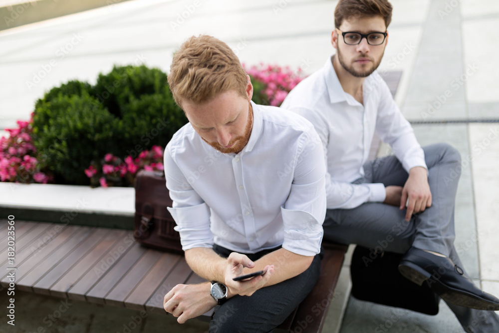 Business colleagues sitting on bench outdoors Business colleagues sitting on bench outdoors
