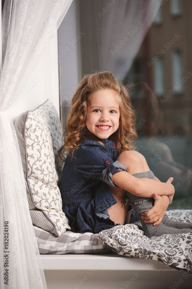 Fototapeta premium little girl on the windowsill at home