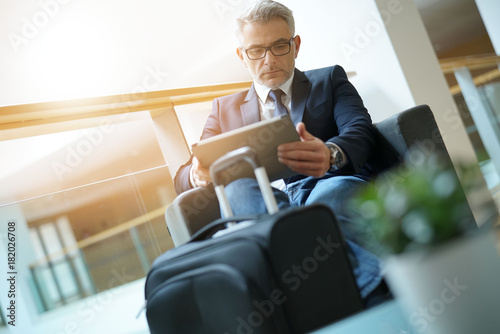 Businessman in airport waiting area connected with tablet