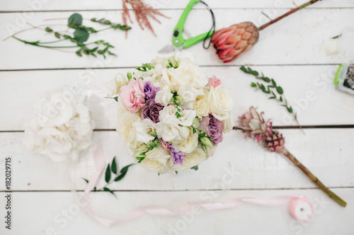 Gorgeous wedding bouquet of roses and other flowers stands on the florist's working table