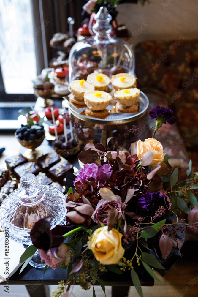 Dishes with cookies, eclairs, macaroons and other sweets made of chocolate and cream served on black table