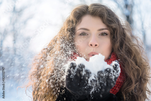 Woman blows on snow in her hands