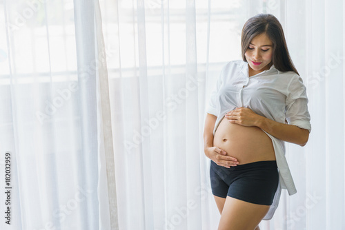 Beautiful pregnant woman standing and hand touch belly at living room. concept of pregnancy, family and lover relation. Free Download Beautiful pregnant woman standing and hand touch belly at living room. concept of pregnancy, family and lover relation. - GFXLoad