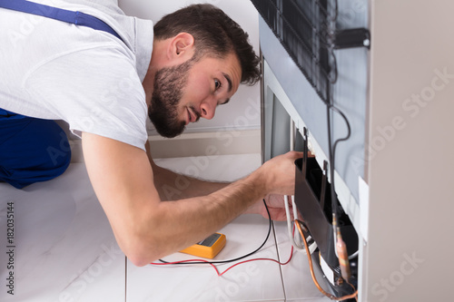 Male Technician Examining Refrigerator