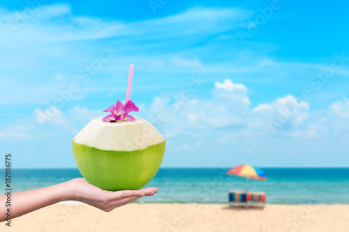 Fototapeta Naklejka Na Ścianę i Meble -  Hand holding fresh coconuts with drinking straw and copy space background