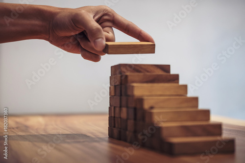 Alternative risk concept, plan and strategy in business, Risk To Make Business Growth Concept With Wooden Blocks, hand of man has piling up and stacking a wooden block photo