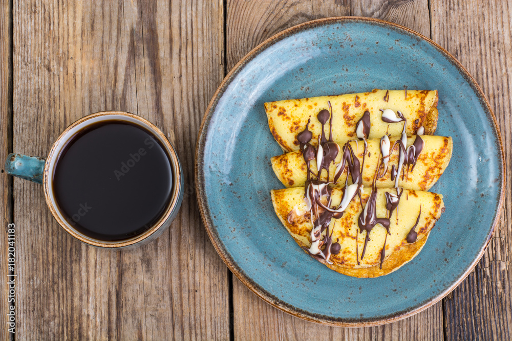 Pancakes stuffed with chocolate sauce, for breakfast on wooden table Pancakes stuffed with chocolate sauce, for breakfast on wooden table