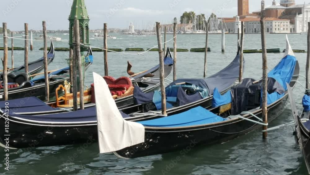 Beautiful black gondolas stand and rock on the waves of Grand Canal in Venice Beautiful black gondolas stand and rock on the waves of Grand Canal in Venice