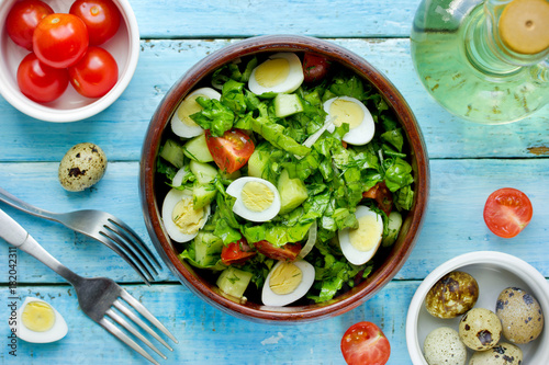 Green vegetable salad with cherry tomatoes quail eggs and olive oil dressing