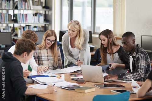 Female Teacher Working With College Students In Library