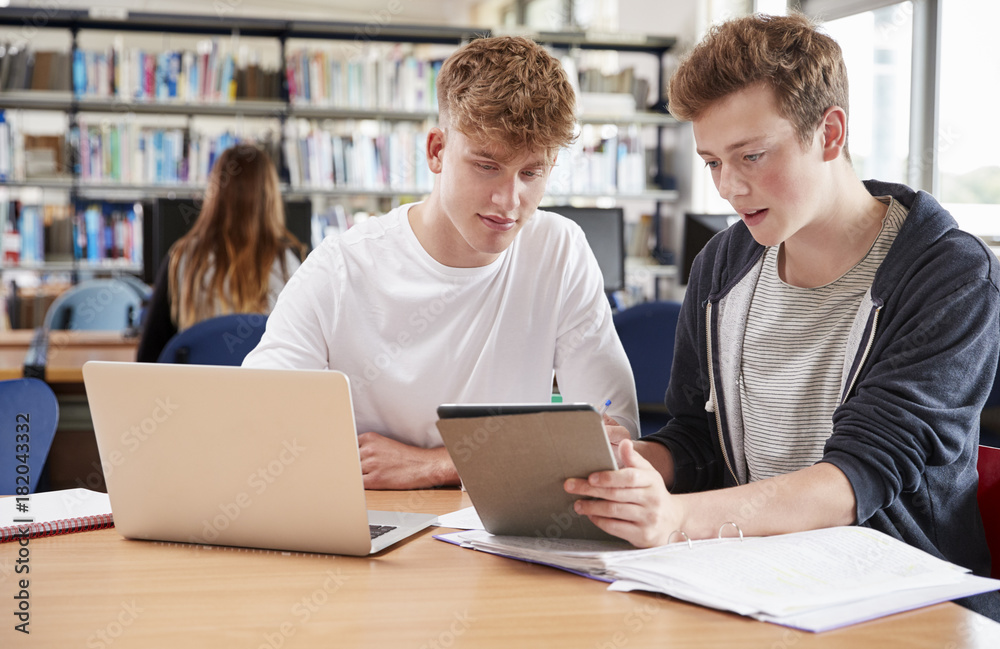Two Male College Students Collaborating On Project In Library Two Male College Students Collaborating On Project In Library