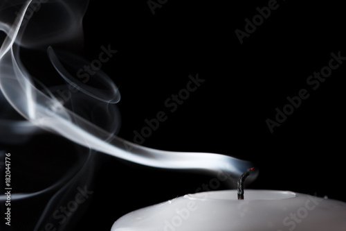 Smoke and extinct candle on a black background