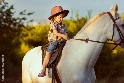 the girl in a hat sits on a horse