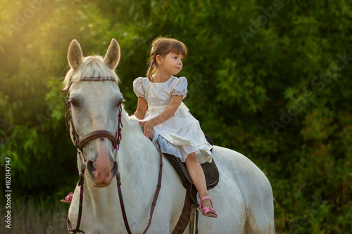 the little girl sits on a horse astride