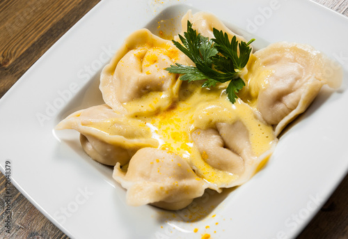 Meat dumplings - russian pelmeni, ravioli with meat on a wooden background.