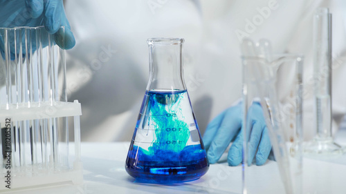 Close-up of conical flask with blue liquid, chemical experiment at laboratory