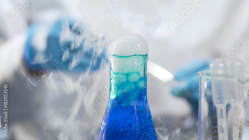 Production of detergent, blue liquid boiling and fuming in flask, chemistry photo