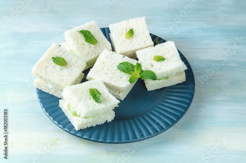 Plate of cucumber sandwiches on teal blue background