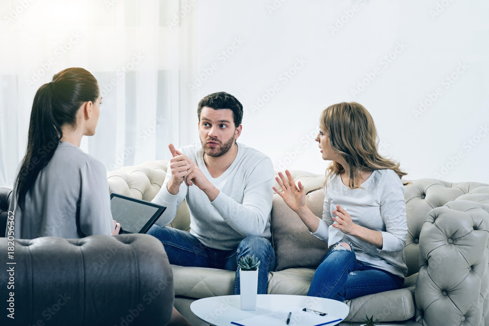 Problems in relationships. Nice pleasant young couple discussing their problems and having an argument while visiting a psychologist Problems in relationships. Nice pleasant young couple discussing their problems and having an argument while visiting a psychologist