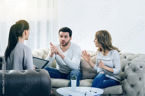 Problems in relationships. Nice pleasant young couple discussing their problems and having an argument while visiting a psychologist