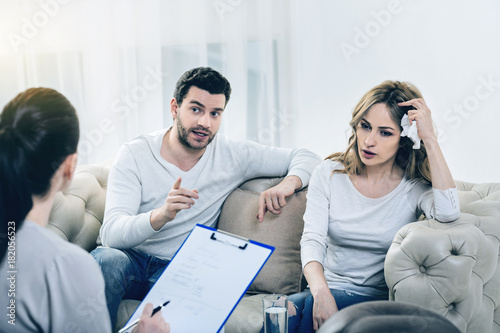 This is our problem. Nice bearded young man talking to the therapist and explaining their problem while sitting together with his girlfriend
