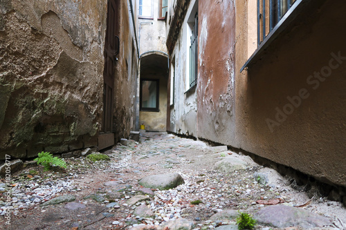 Fototapeta Naklejka Na Ścianę i Meble -  A narrow courtyard in an old European town. Bottom view. Ancient stone paving stones