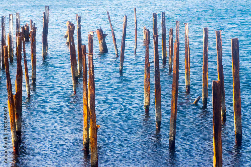 Old rusty pipes from the old pier in blue calm water with shallow ripples Old rusty pipes from the old pier in blue calm water with shallow ripples