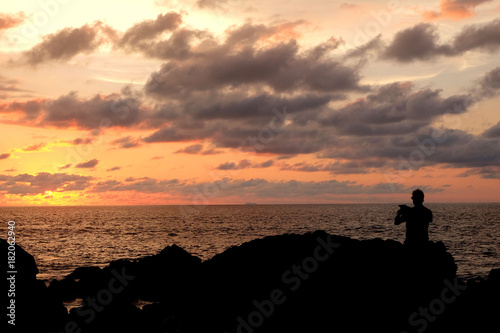 silhouette of men take a photograph at the sunset