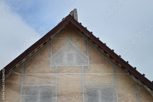 New house wall facade insulation against blue sky. Roof or attic warming with mineral wool.