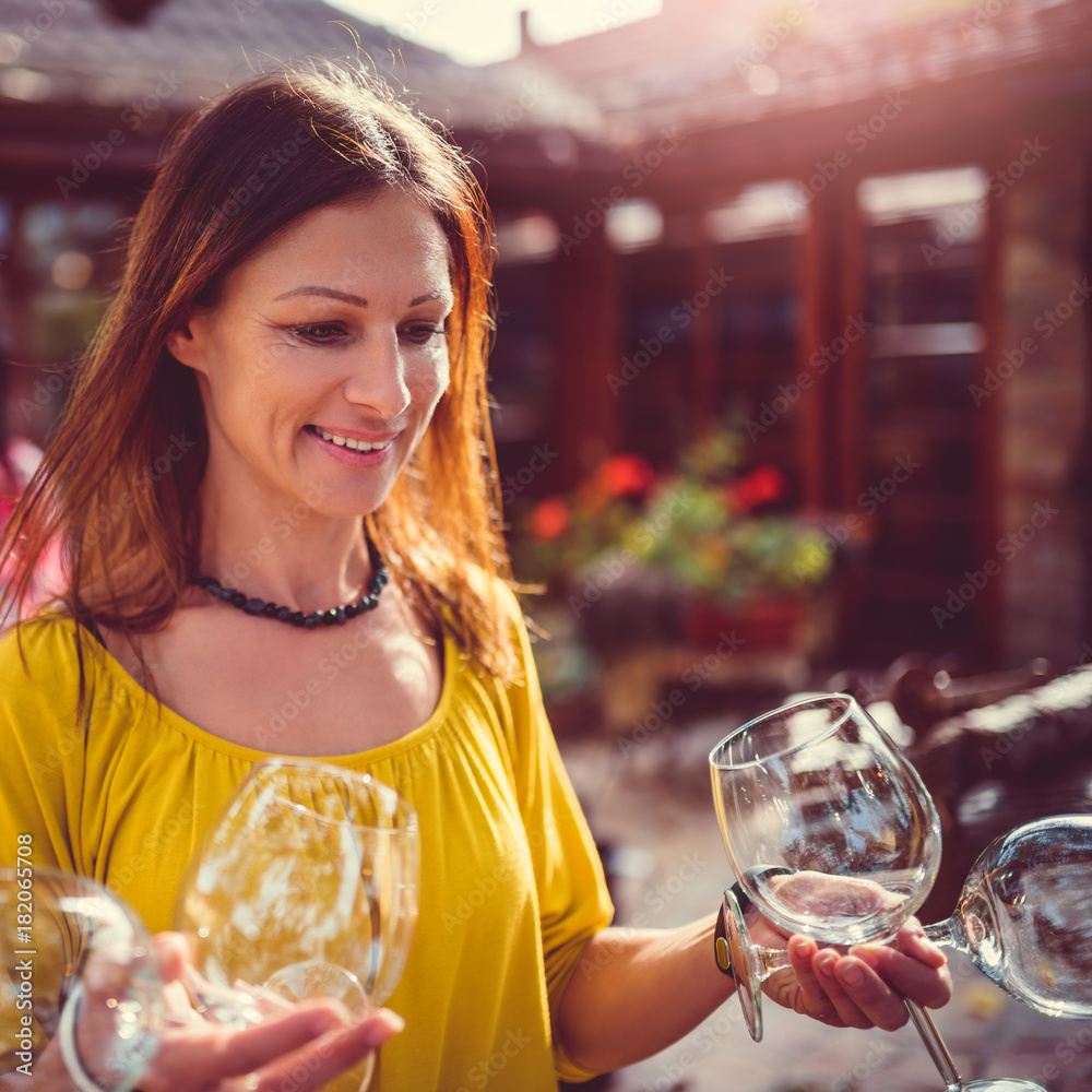 Fototapeta premium Woman carrying wine glasses at backyard patio