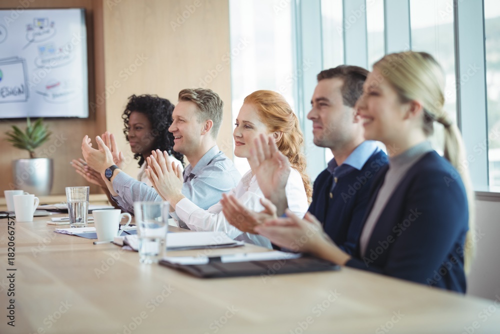 Happy business people clapping at conference table during