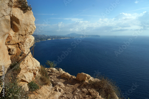 A stony path at the edge of the mountain, below is a blue sea