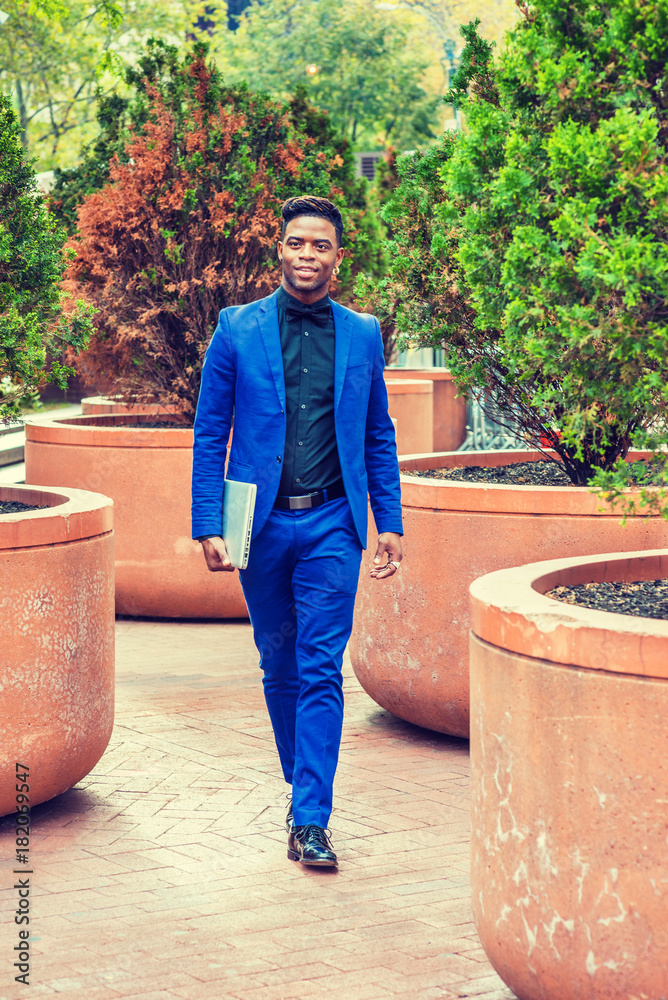 African American Business Man travels, works in New York. Wearing blue  suit, black shirt, bow tie,