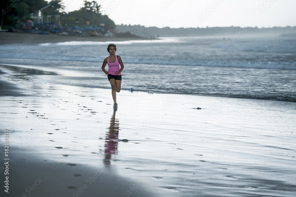 young attractive and fit Asian sport runner woman running on beach sea side smiling happy in fitness