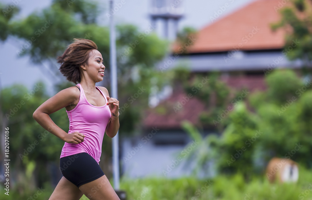 young attractive Asian sport runner woman running in the jungle smiling happy in training workout on herb background in fitness young attractive Asian sport runner woman running in the jungle smiling happy in training workout on herb background in fitness