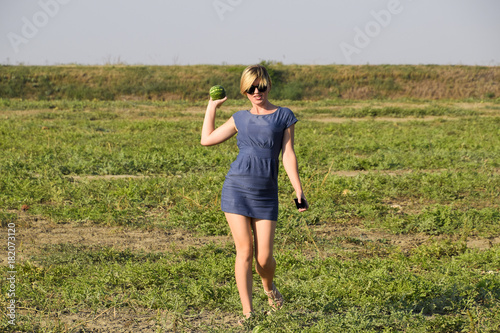 Girl with a watermelon in her hand. Search for watermelons in the field of melons. Found a watermelon.