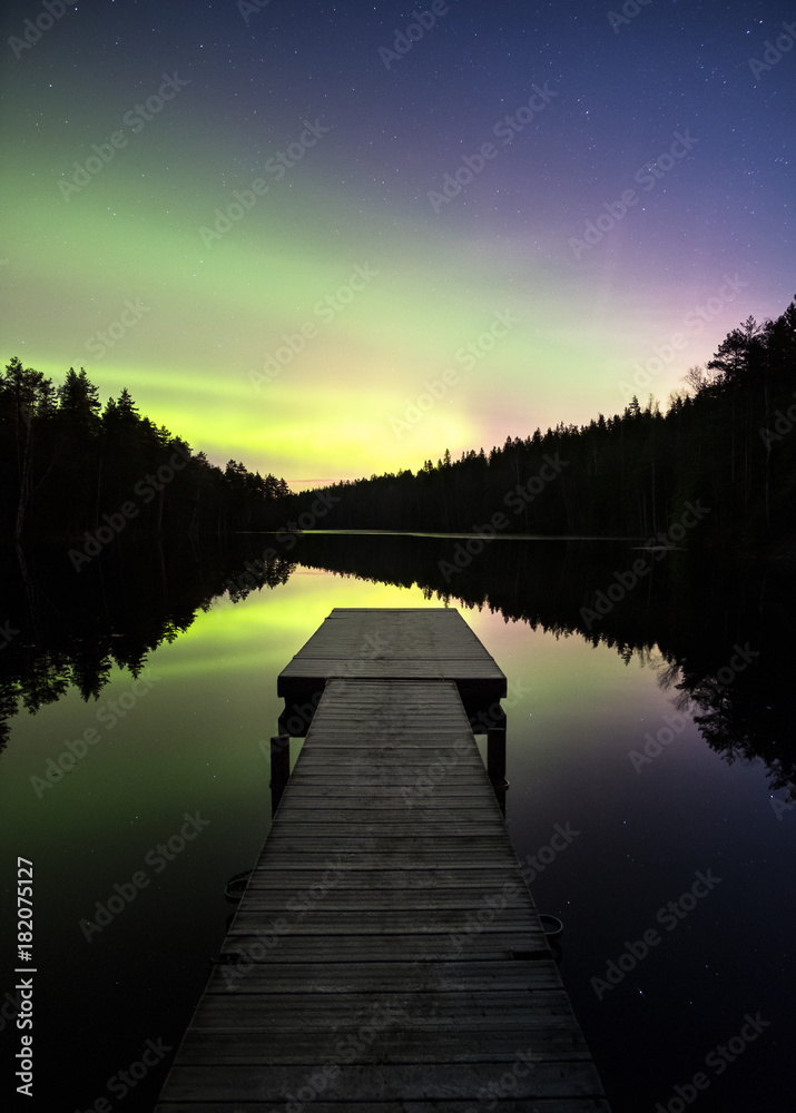 Scenic aurora borealis with nice reflections and pier at night in Finland