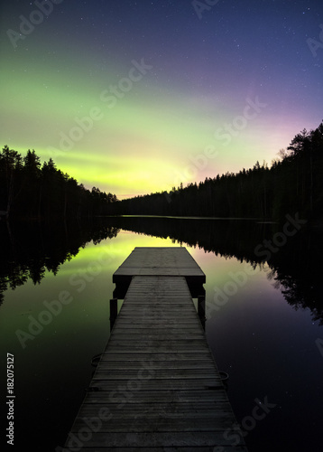 Scenic aurora borealis with nice reflections and pier at night in Finland