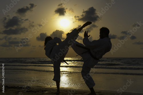 Karate fighters at sunset on the beach