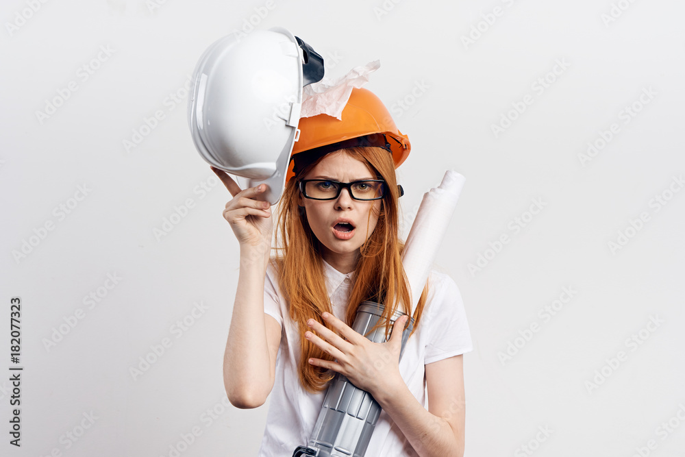 Builder woman in an orange helmet on a gray background Builder woman in an orange helmet on a gray background